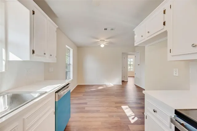 a view of an empty room with kitchen stove and cabinets