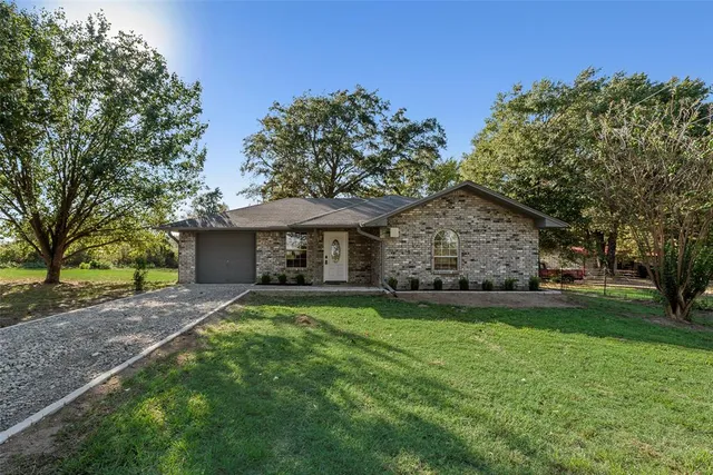 a front view of a house with a garden and trees