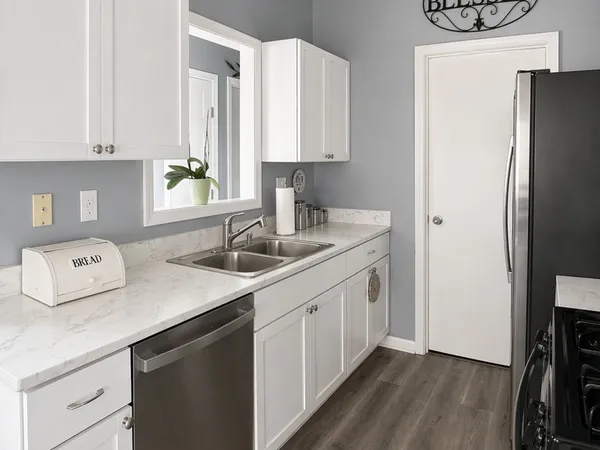 a kitchen with stainless steel appliances a sink a refrigerator and a stove with wooden floor
