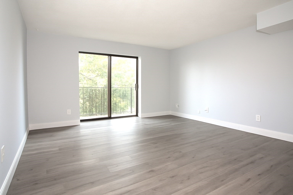 305 Riverside Avenue, Unit 41 Medford, MA 02155 - Photo 4 of 12 a view of an empty room with wooden floor and a window
