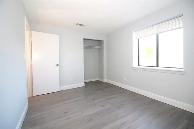 an empty room with wooden floor and windows