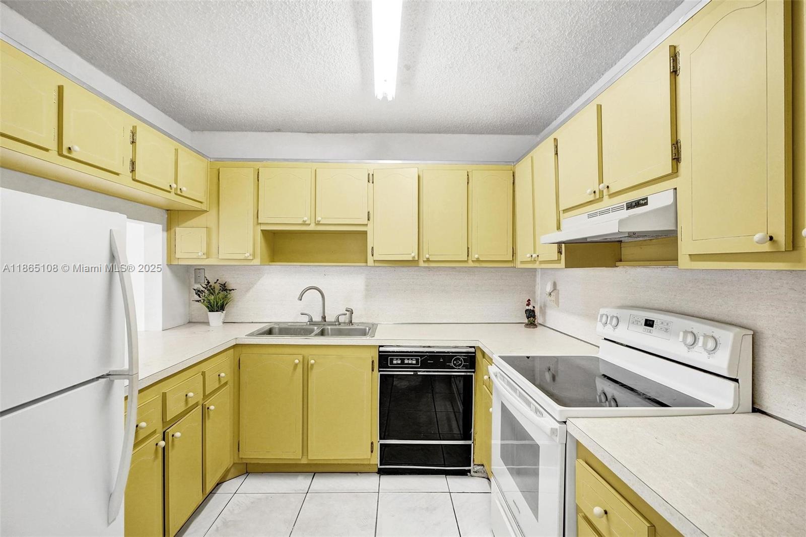 1900 West 68th Street, Unit C203 Hialeah, FL 33014 - Photo 8 of 29 a kitchen with a sink a stove top oven and cabinets