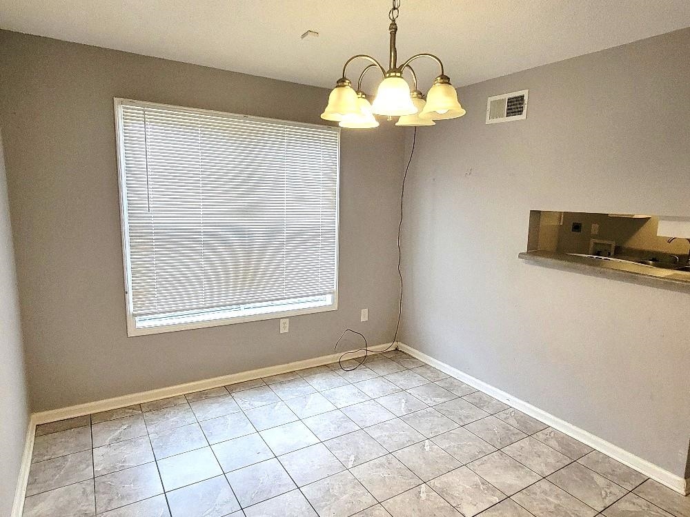 4063 Double Tree Road Memphis, TN 38109 - Photo 4 of 14 Unfurnished dining area featuring light tile patterned floors and a chandelier