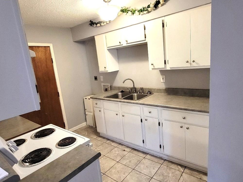 4063 Double Tree Road Memphis, TN 38109 - Photo 6 of 14 Kitchen featuring white cabinetry, sink, white electric stove, a textured ceiling, and light tile patterned flooring