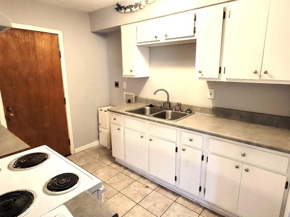 4063 Double Tree Road Memphis, TN 38109 - Photo 7 of 14 Kitchen with sink, white cabinets, light tile patterned floors, and white electric range