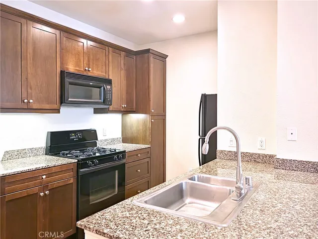 a kitchen with granite countertop a stove sink and microwave