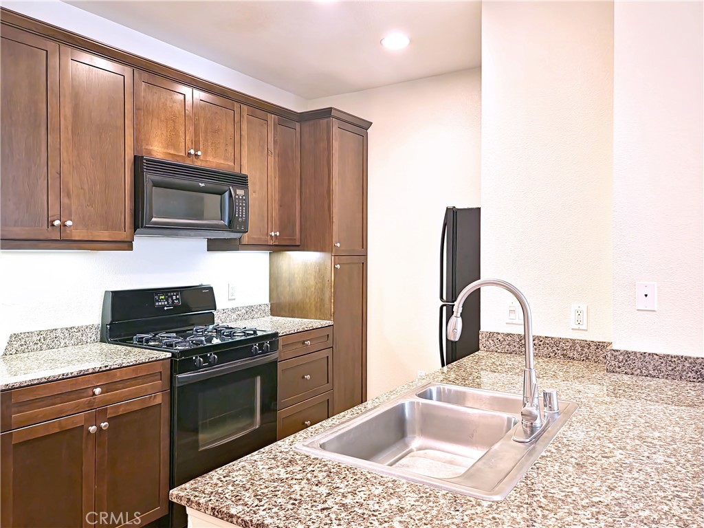 a kitchen with granite countertop a stove sink and microwave
