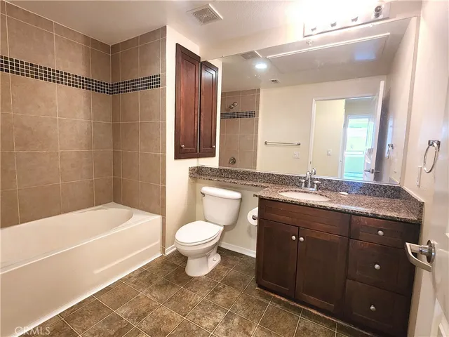 a bathroom with a granite countertop sink toilet mirror and bathtub