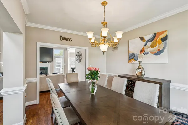 a kitchen with stainless steel appliances granite countertop a refrigerator a stove a kitchen island a dining table and chairs with wooden floor