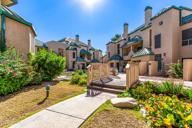 a front view of a multi story residential apartment building with yard and car parked