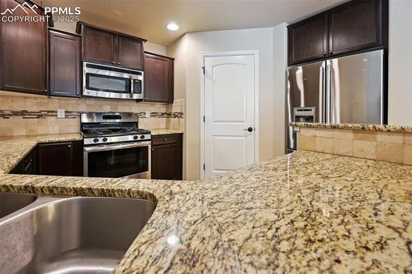 a kitchen with stainless steel appliances granite countertop a refrigerator a stove and a sink with wooden floor