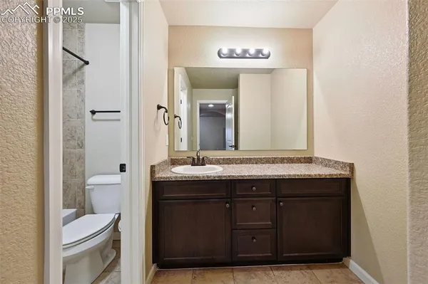 a bathroom with a granite countertop sink a toilet and a mirror