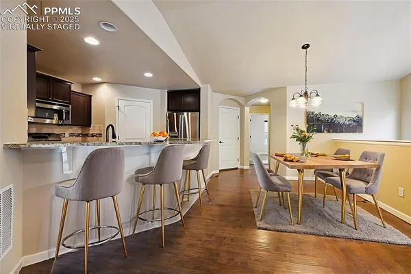 a dining room with furniture a chandelier and wooden floor