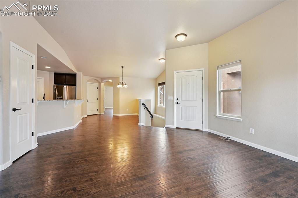 5384 Oak Spring Heights Colorado Springs, CO 80923 - Photo 6 of 19 a view of an empty room with wooden floor and a kitchen