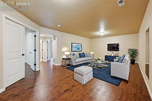 a living room with couches couches and a flat screen tv with kitchen view