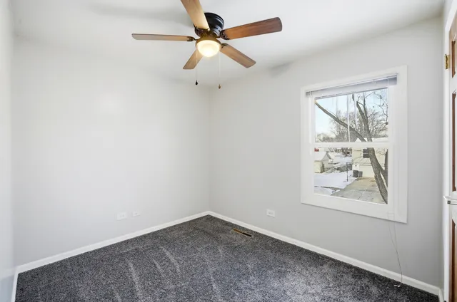 an empty room with windows and ceiling fan