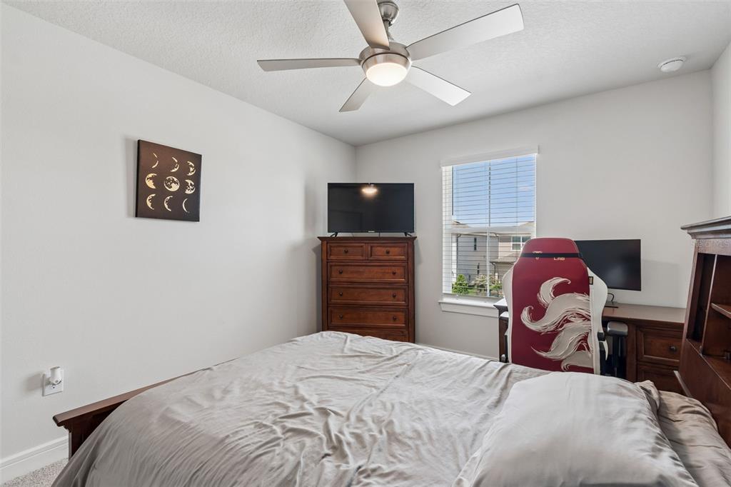 6608 Ryestone Way Wesley Chapel, FL 33545 - Photo 33 of 66 a bedroom with a bed dresser and a flat tv screen
