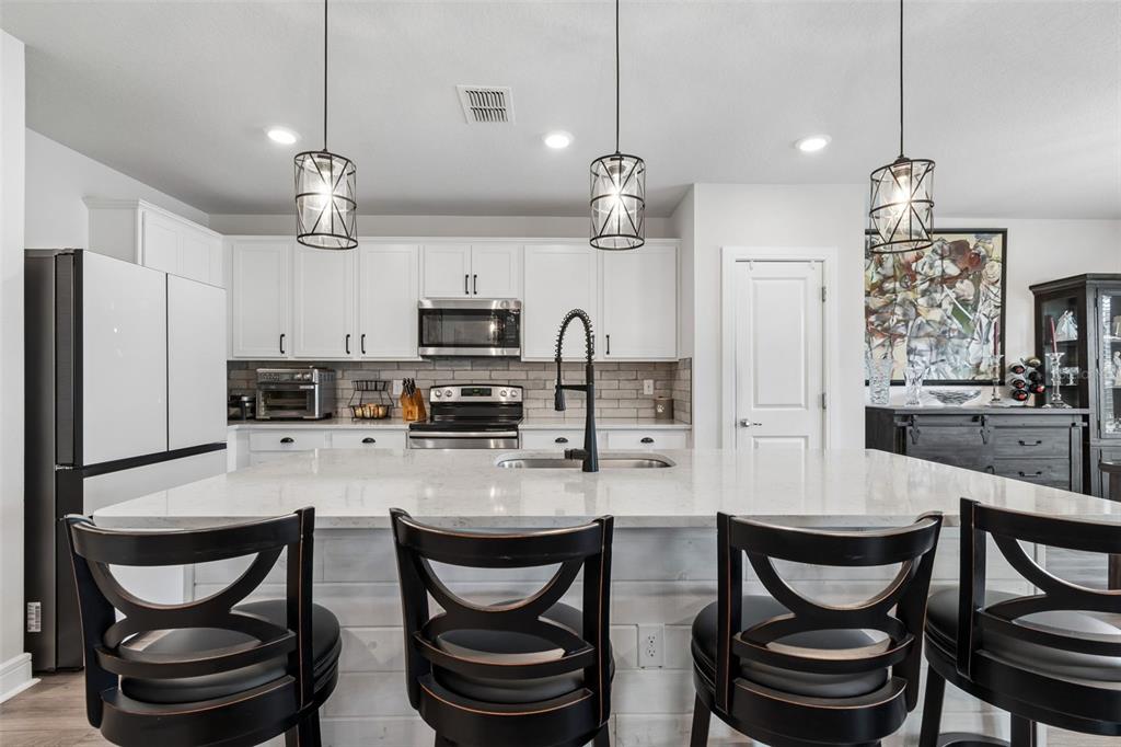 6608 Ryestone Way Wesley Chapel, FL 33545 - Photo 4 of 66 a kitchen with stainless steel appliances a dining table chairs and refrigerator