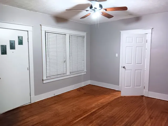 a view of an empty room with wooden floor and a window