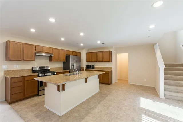 a kitchen with stainless steel appliances a stove top oven a sink a refrigerator and white cabinets