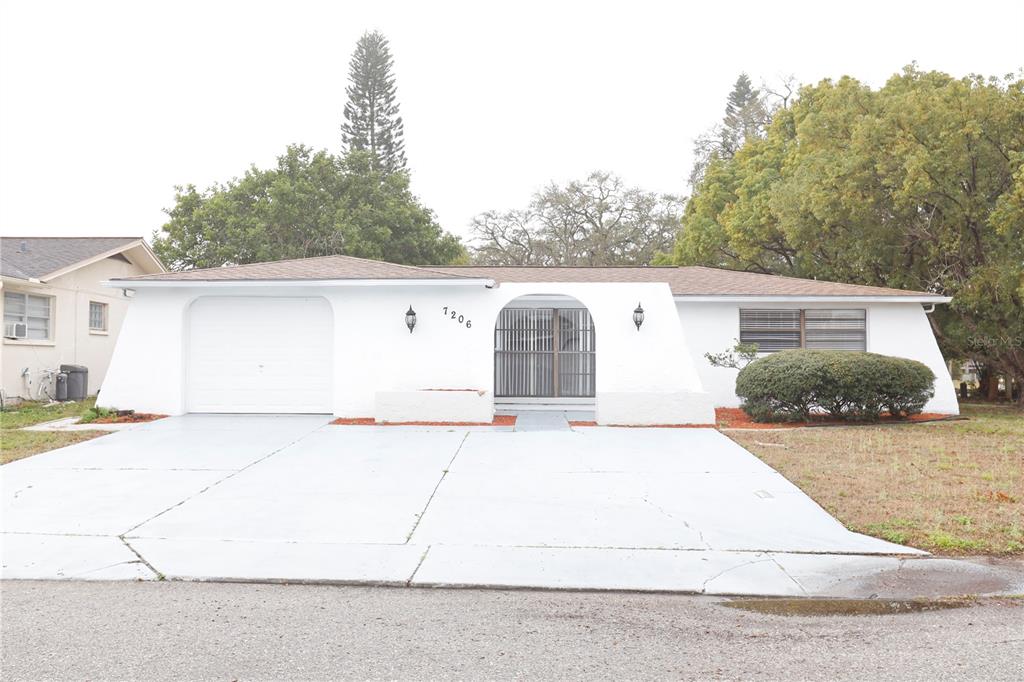 7206 San Moritz Drive Port Richey, FL 34668 - Photo 1 of 1 a view of a white house with large trees and outdoor space