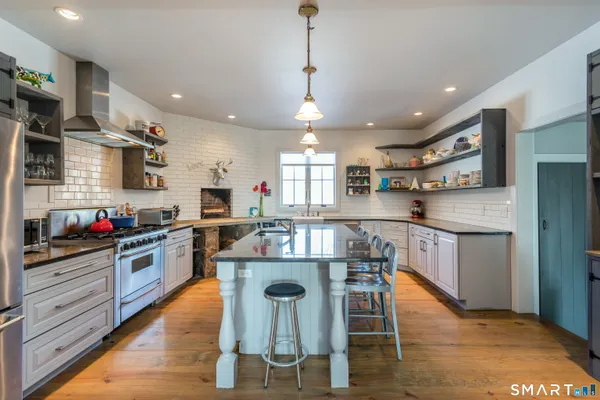 a kitchen with kitchen island stainless steel appliances a stove a sink a refrigerator cabinets and living room view