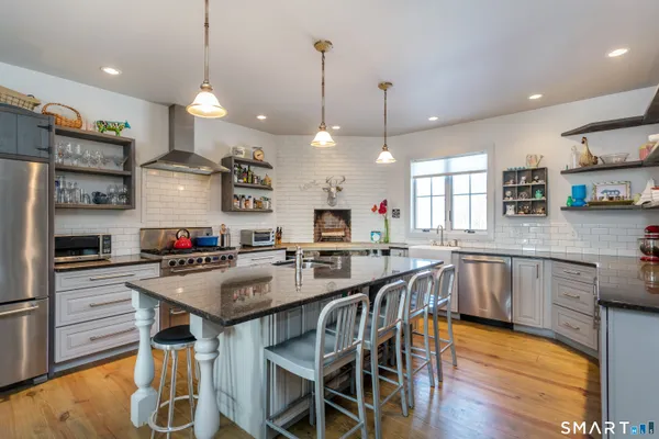 a kitchen with stainless steel appliances granite countertop a kitchen island a stove a table and chairs in it