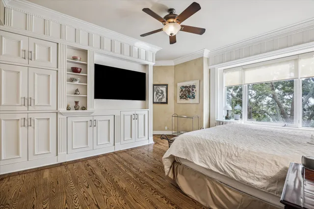 a bedroom with a bed a flat tv screen and a bookshelf