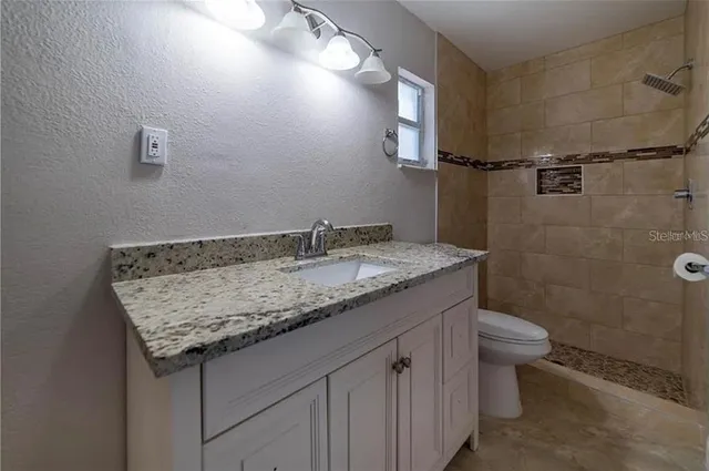 a bathroom with a granite countertop sink a toilet and shower
