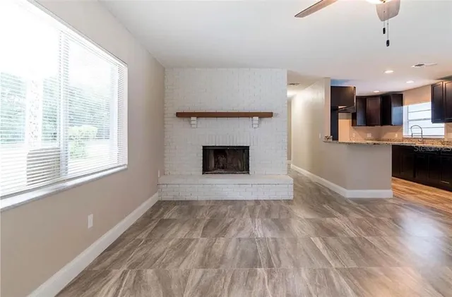 a view of empty room with kitchen and fireplace