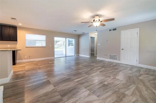 a view of an empty room with a window and wooden floor
