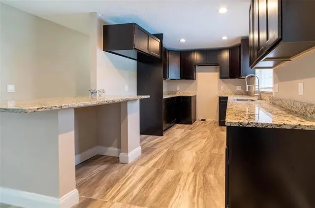 a large kitchen with stainless steel appliances kitchen island granite countertop a sink refrigerator and cabinets