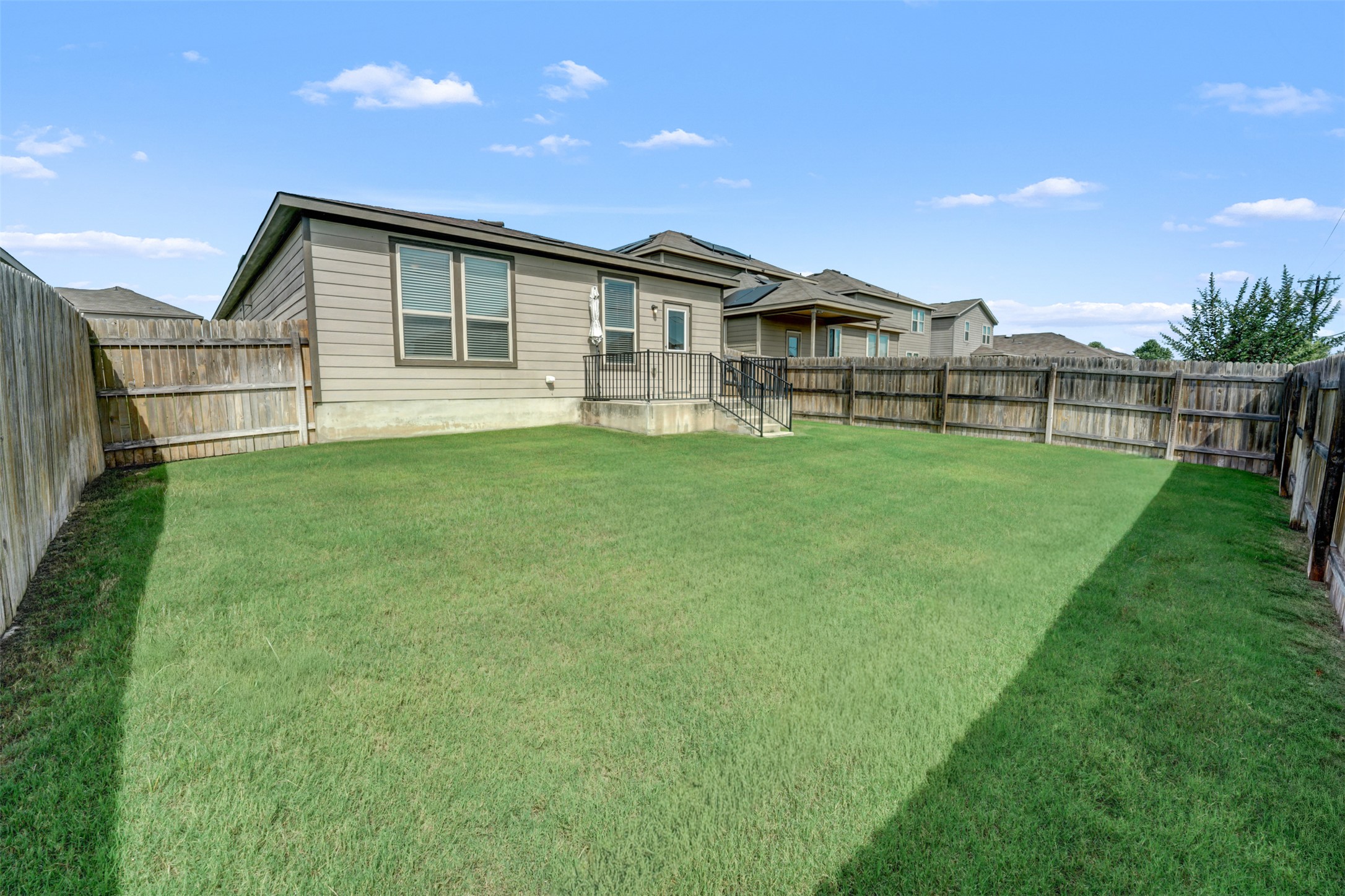 213 Ibis Falls Loop Jarrell, TX 76537 - Photo 29 of 37 A fenced backyard offers a green lawn and a small patio, perfect for outdoor enjoyment.