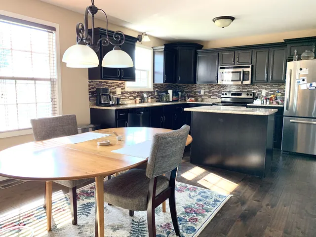 a kitchen with stainless steel appliances granite countertop a dining table chairs stove refrigerator and cabinets