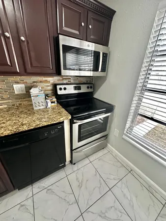 a kitchen with granite countertop a stove and a microwave