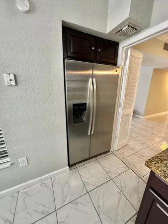 a view of a refrigerator in kitchen and an empty room