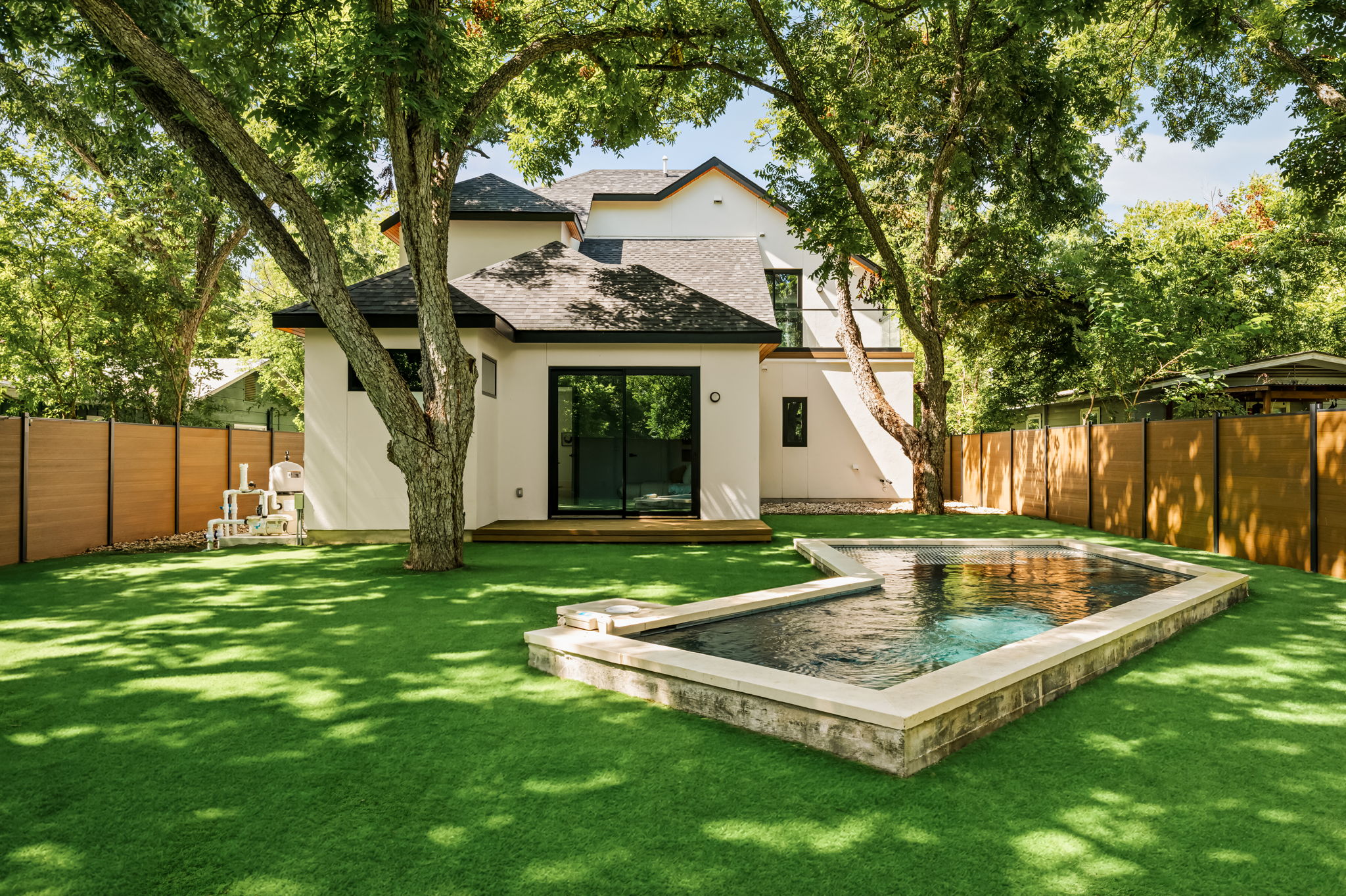 3210 Thompson Street Austin, TX 78702 - Photo 14 of 39 A private yard with a refreshing pool, surrounded by mature trees and a modern home exterior.