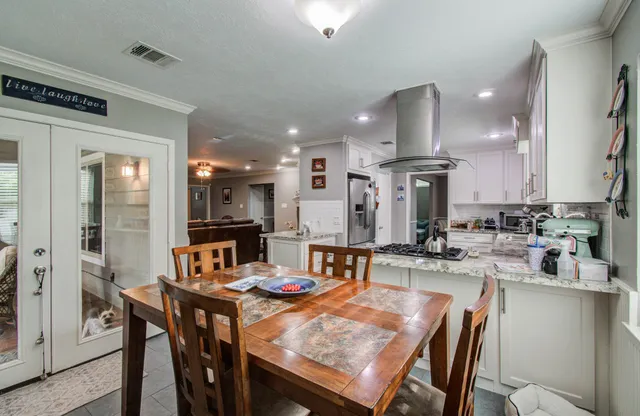 a kitchen with a dining table chairs and refrigerator