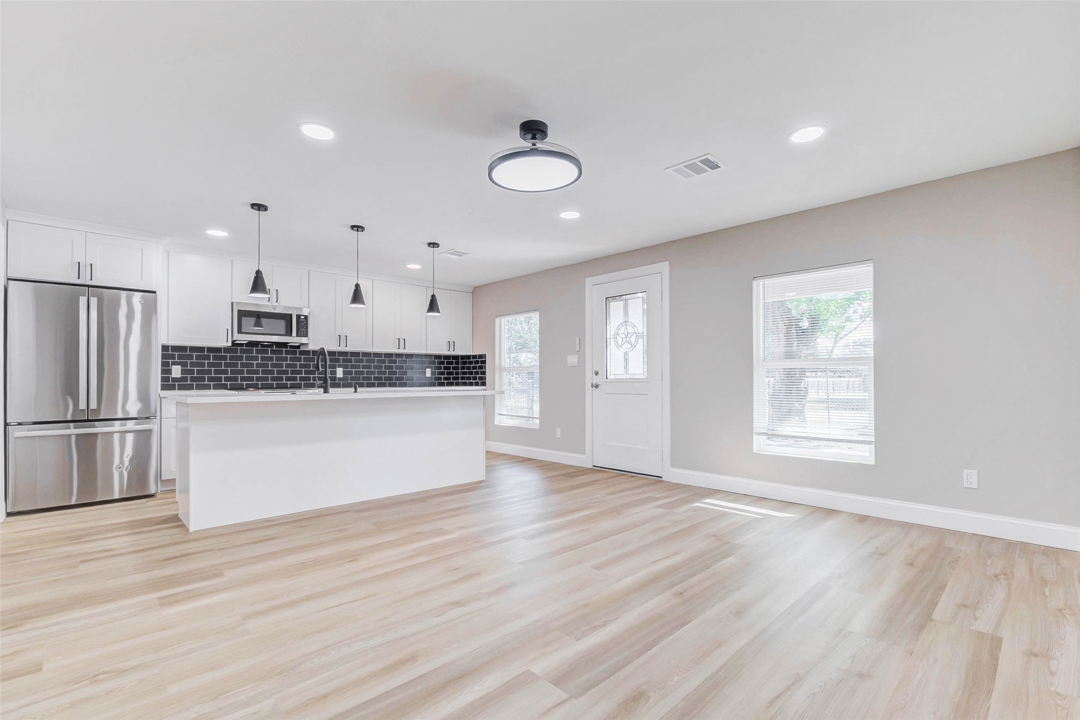 1054 Dewalt Street Houston, TX 77088 - Photo 13 of 24 a large kitchen with kitchen island a stove a refrigerator a sink dishwasher and white cabinets with wooden floor