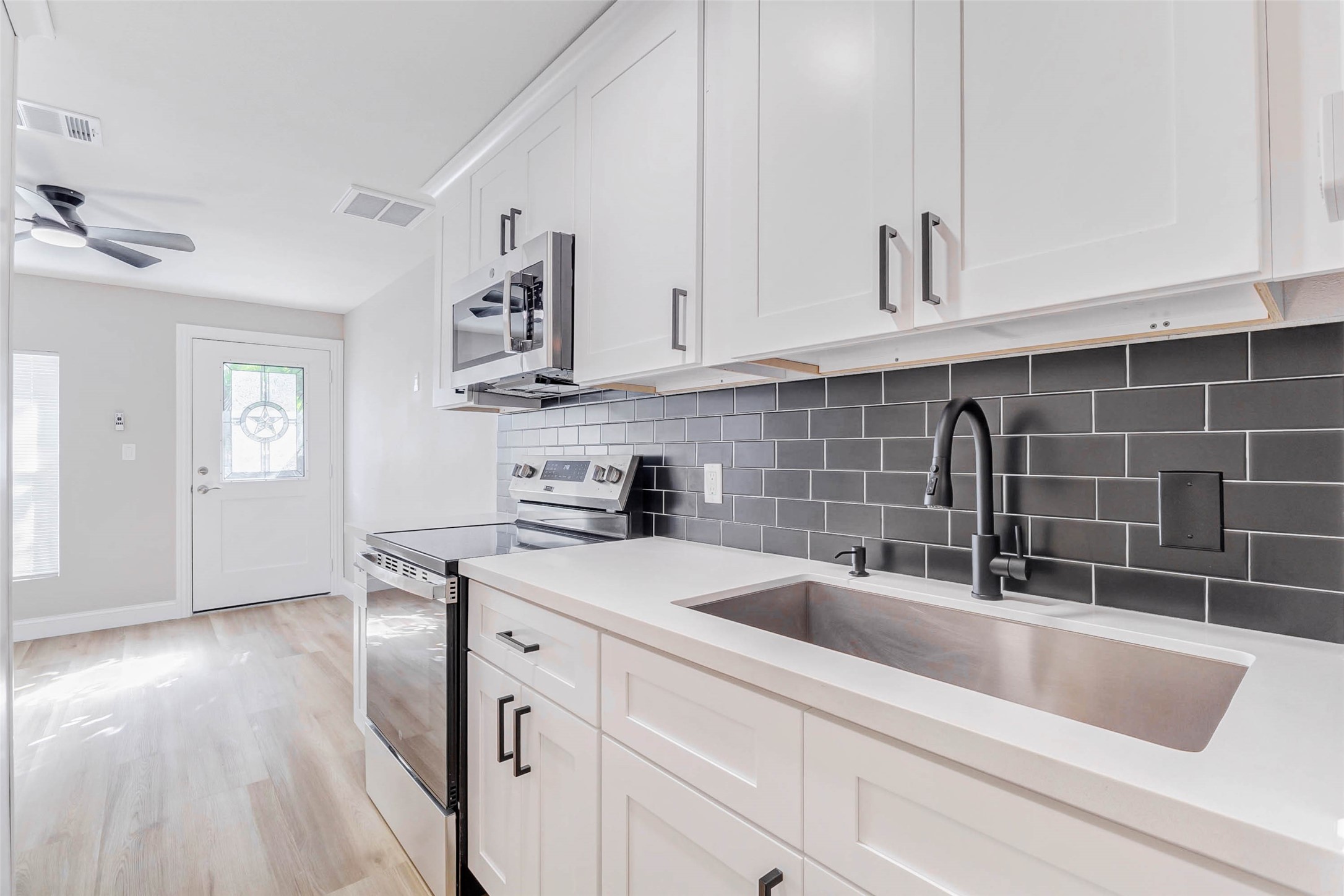 1054 Dewalt Street Houston, TX 77088 - Photo 8 of 24 a kitchen with stainless steel appliances granite countertop a sink dishwasher a stove and white cabinets with wooden floor