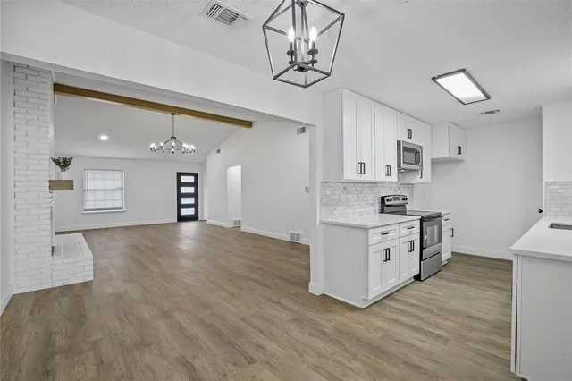 a kitchen with stainless steel appliances granite countertop a sink cabinets and wooden floor