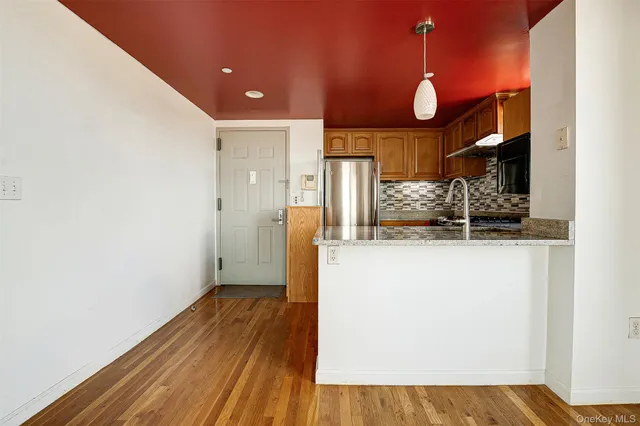 a kitchen with stainless steel appliances granite countertop a refrigerator a stove and a sink with wooden floors