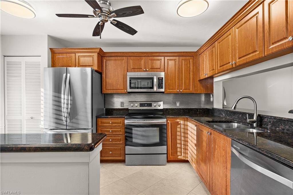 3012 Sandpiper Bay Circle, Unit D302 Naples, FL 34112 - Photo 4 of 16 a kitchen with stainless steel appliances granite countertop a stove sink and microwave