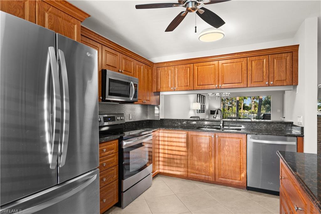 3012 Sandpiper Bay Circle, Unit D302 Naples, FL 34112 - Photo 5 of 16 a kitchen with stainless steel appliances granite countertop a refrigerator a stove a sink and a microwave