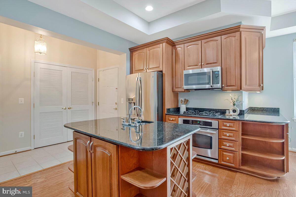 735 Runabout Loop, Unit 735 Solomons, MD 20688 - Photo 8 of 51 a kitchen with stainless steel appliances granite countertop a stove top oven a sink a dining table and chairs with wooden floor
