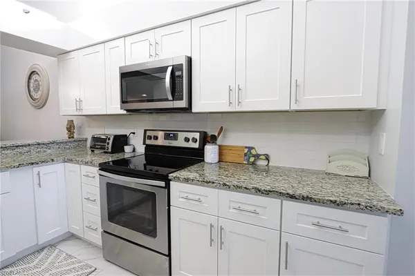 a kitchen with granite countertop white cabinets and stainless steel appliances