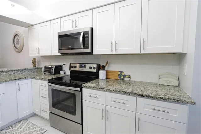 a kitchen with granite countertop white cabinets and stainless steel appliances