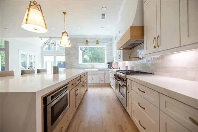 a kitchen with stainless steel appliances granite countertop a sink a stove and a wooden floors