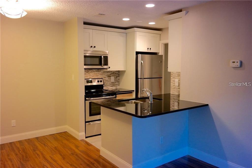 224 Afton Square, Unit 104 Altamonte Springs, FL 32714 - Photo 2 of 13 a kitchen with kitchen island a sink appliances and cabinets
