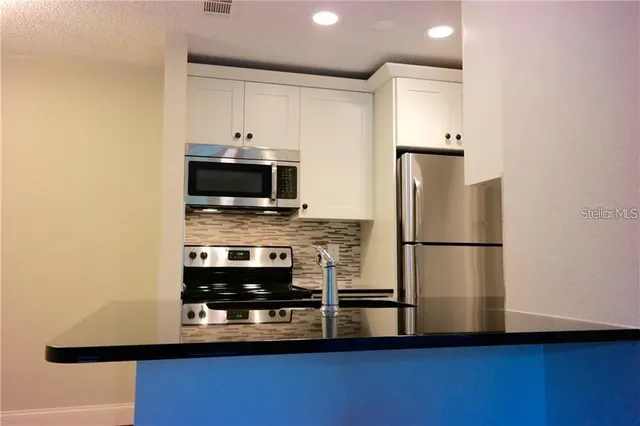 a kitchen with kitchen island a stove a refrigerator and a microwave